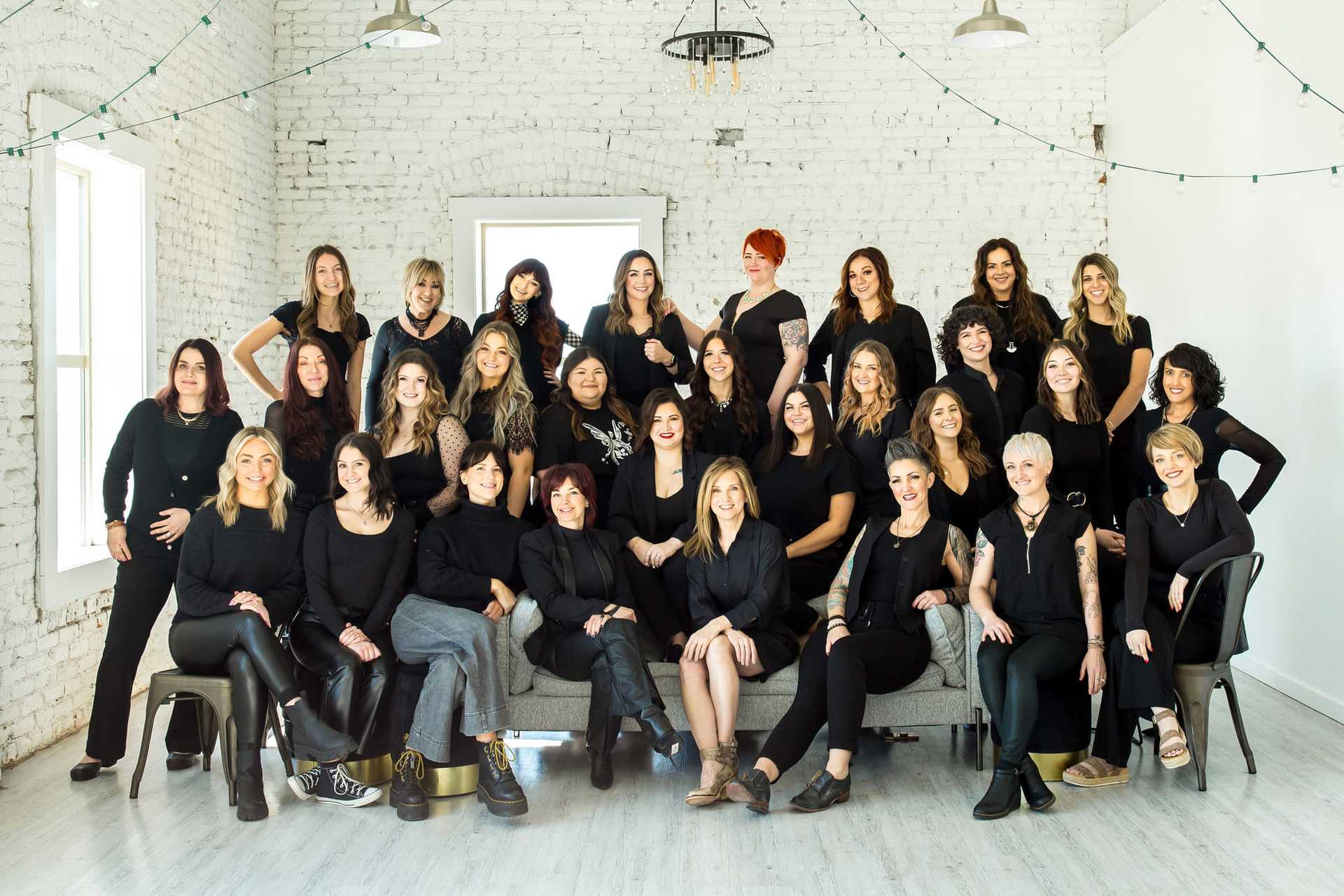 Group of women posing together in a bright room with white walls.